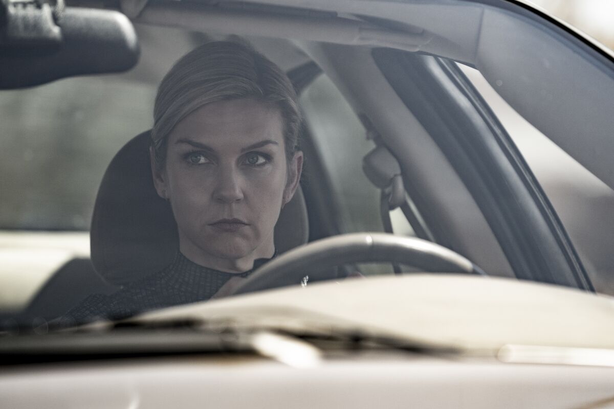 A woman sitting in a parked car looking serious.