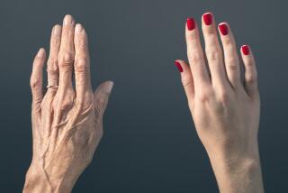 Studio photograph of elderly woman's hand beside a younger woman's hand.