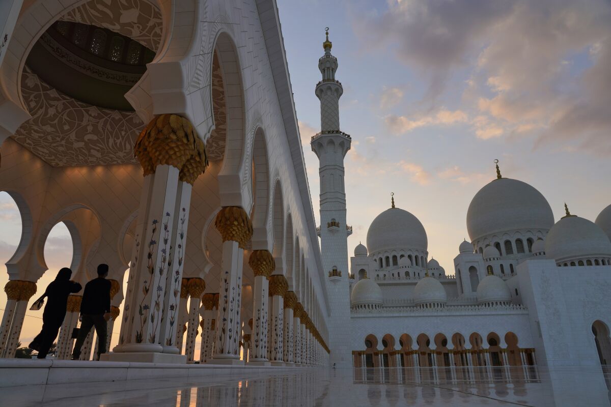FILE - Tourists walk through Sheikh Zayed Grand Mosque at dusk in Abu Dhabi, United Arab Emirates, Wednesday, Dec. 9, 2020. Abu Dhabi, the capital of the United Arab Emirates, has issued new rules governing divorce, inheritance and child custody for non-Muslims, the country's state-run news agency reported Sunday, Nov. 7, 2021. (AP Photo/Jon Gambrell, File)