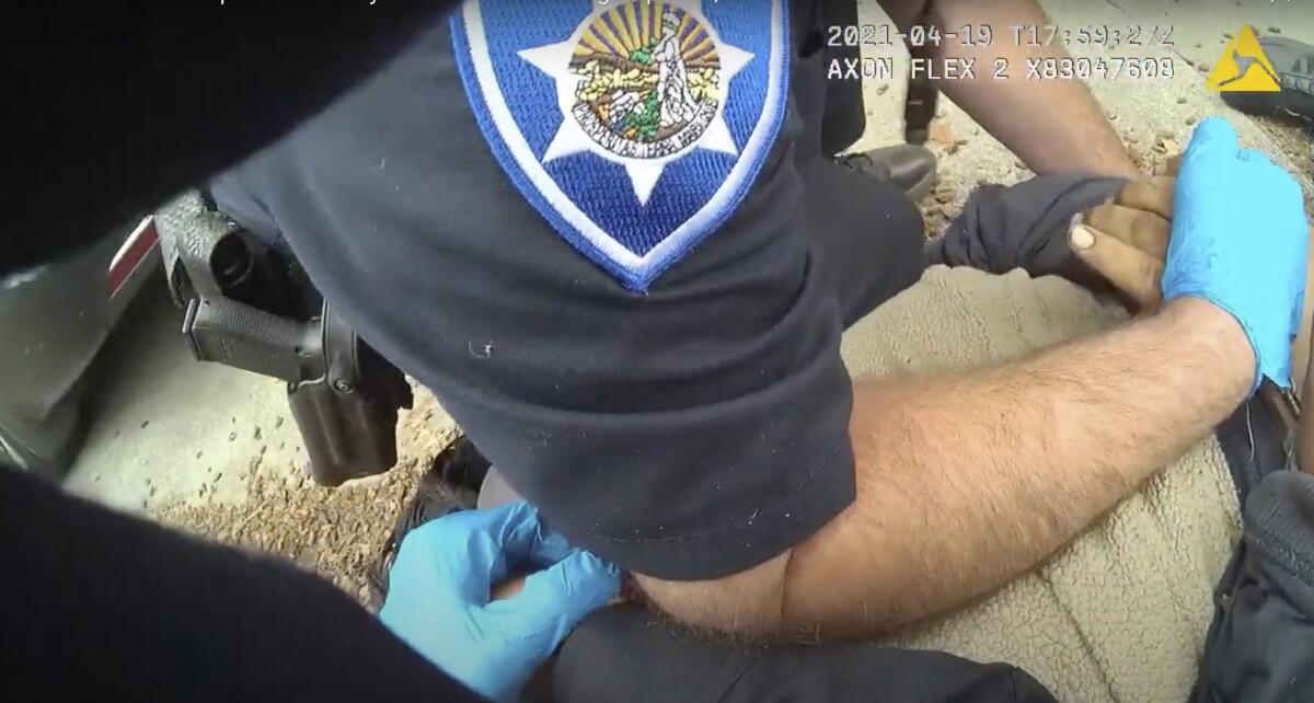 A close-up of a police officer's arm pinning a man's back