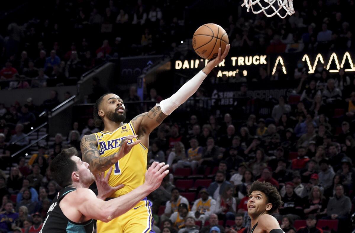 Lakers' D'Angelo Russell drives to the basket against Portland Trail Blazers' Drew Eubanks as Matisse Thybulle looks on.