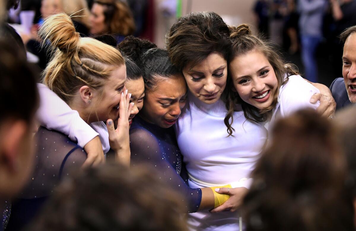 Valorie Kondos Field, second from right, hugs gymnasts, from left, Gracie Kramer, Anna Glenn, Margzetta Frazier and team manager Lila Waller after finishing third in the NCAA championships.