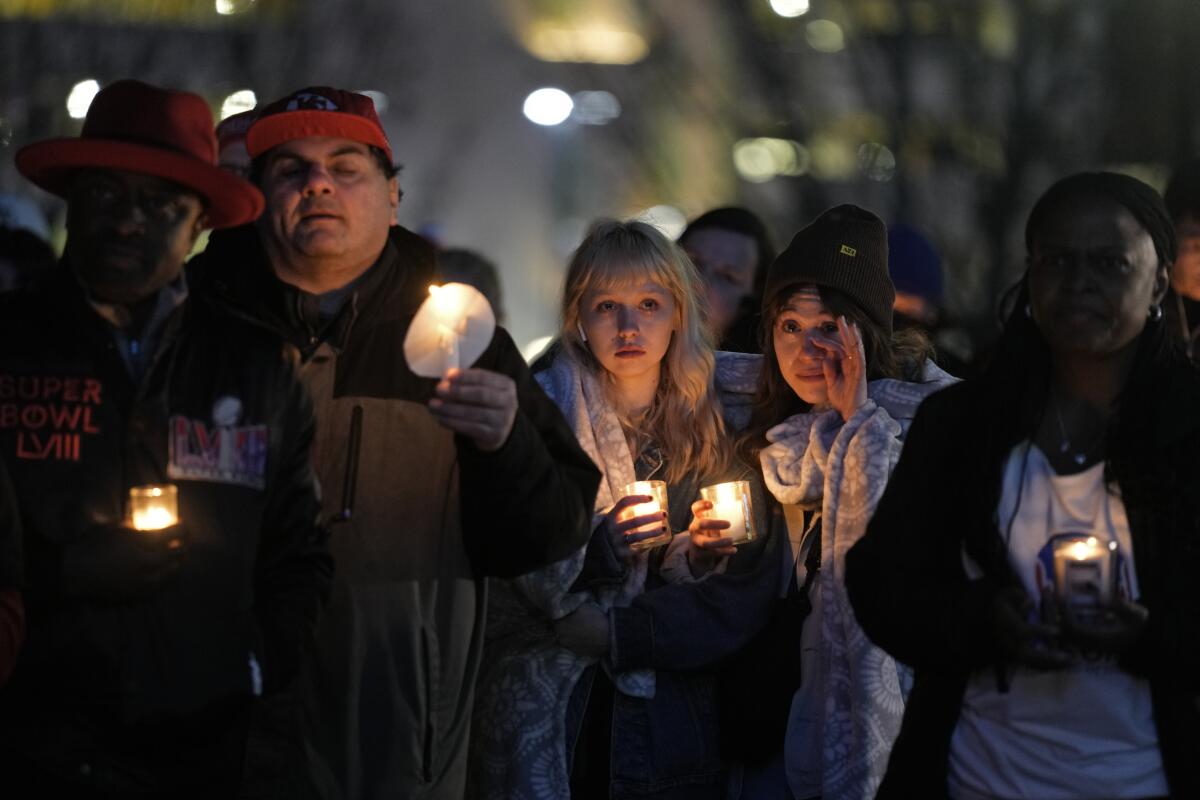 People attend a candlelight vigil at night for victims of a shooting.