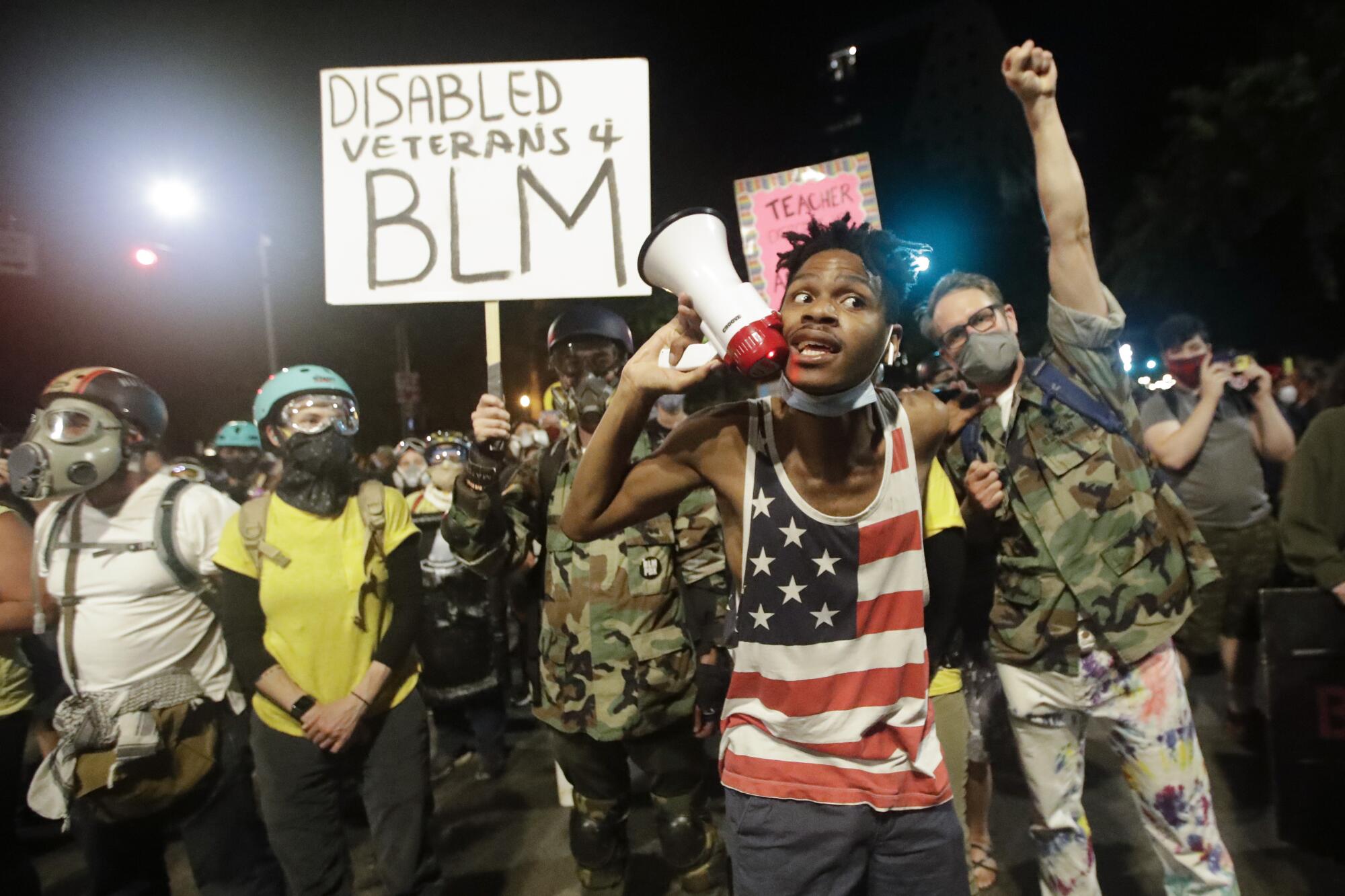 A demonstrator shouts slogans using a bullhorn next to a group of military veterans during a Black Lives Matter protest.