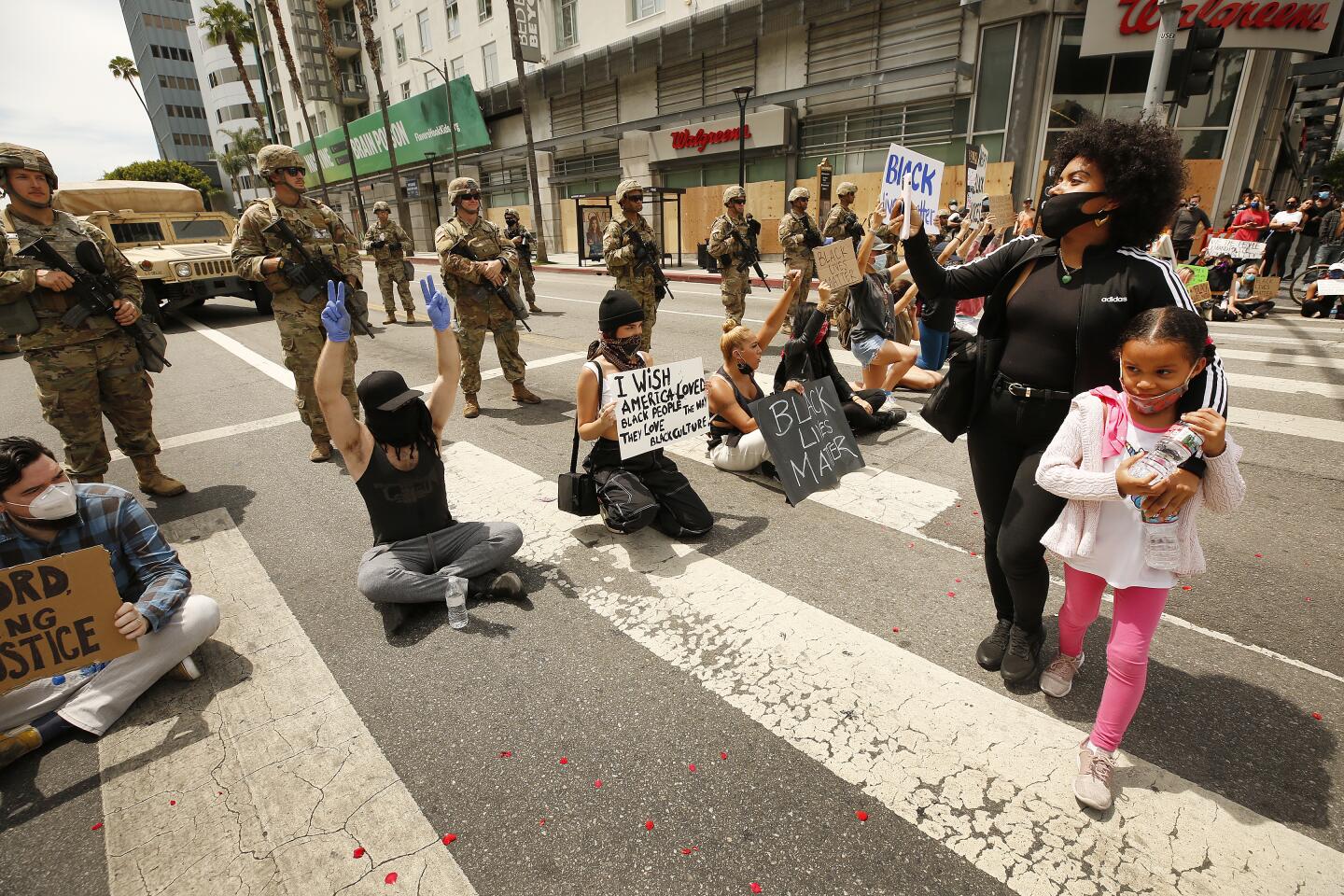 A mother and daughter pass protestors in Hollywood.