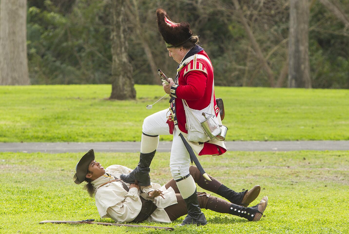 A British soldier steps on a wounded militiamen during a reenactment of the Battle of Lexington and Parkers Revenge at the Huntington Beach Central Park on Saturday, February 10.