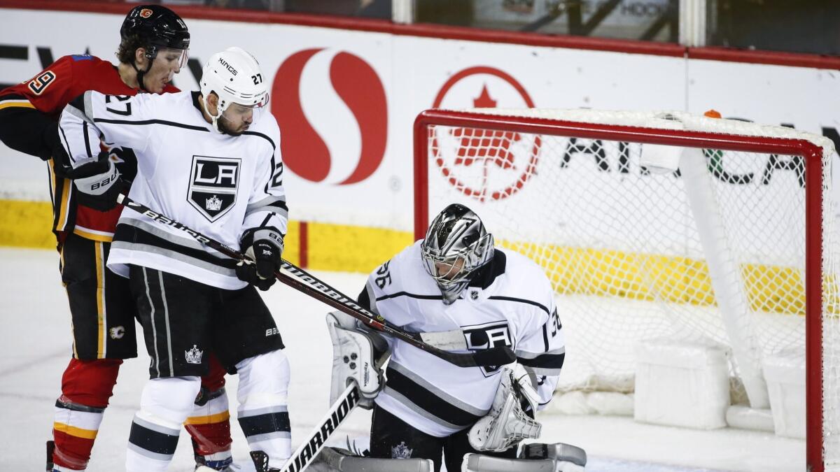 Kings goalie Jack Campbell, right, and teammate Alec Martinez, center, keep Calgary Flames' Matthew Tkachuk away from the net during the second period.