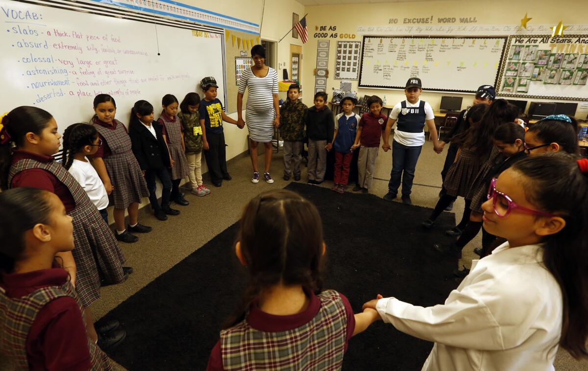 Third-grade teacher Tina Oliver, center, prays with students at the Seventh-day Adventist-affiliated Calexico Mission School in Calexico, Calif.
