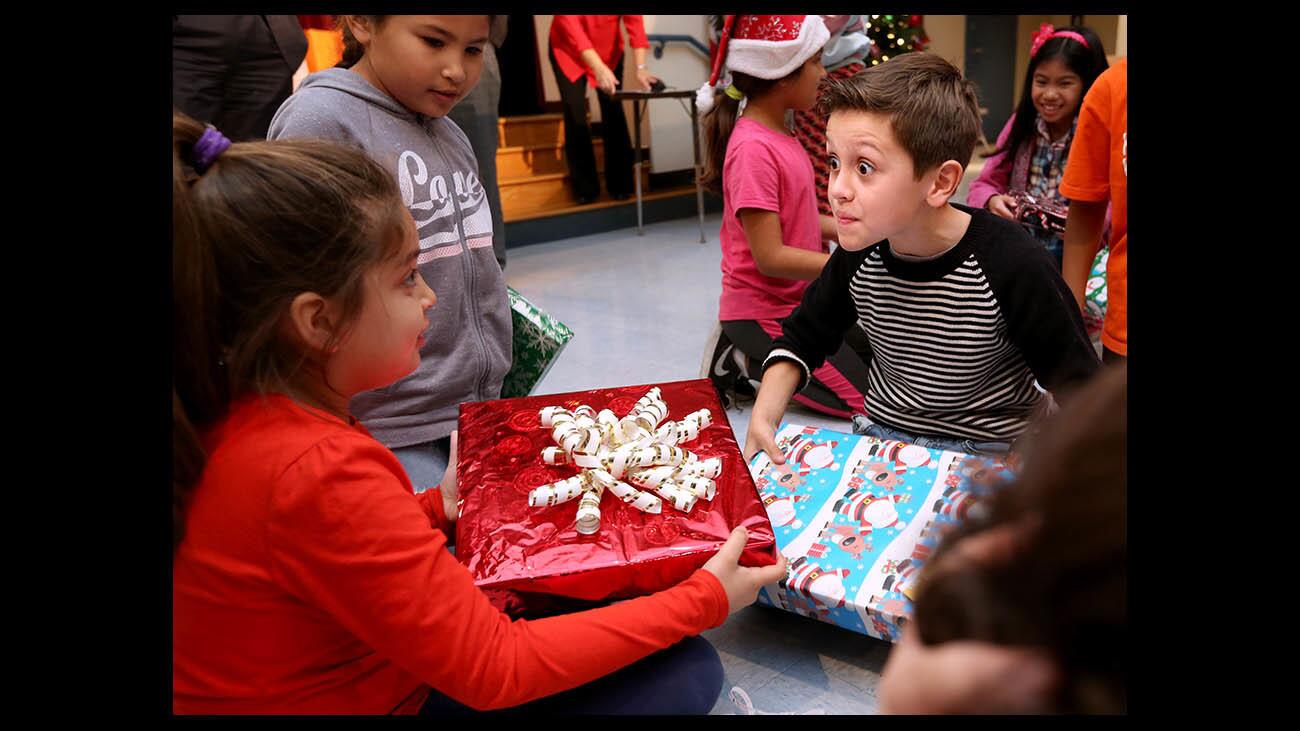 Third grader Alejandro Guerrero, right, shows his excitement with classmates after receiving a gift at the annual Dignity Health Glendale Memorial Hospital and Health Center Gift Donation event, at Cerritos Elementary School in Glendale on Wednesday, Dec. 19, 2018. More than 480 gifts were brought to the school, one for each student.