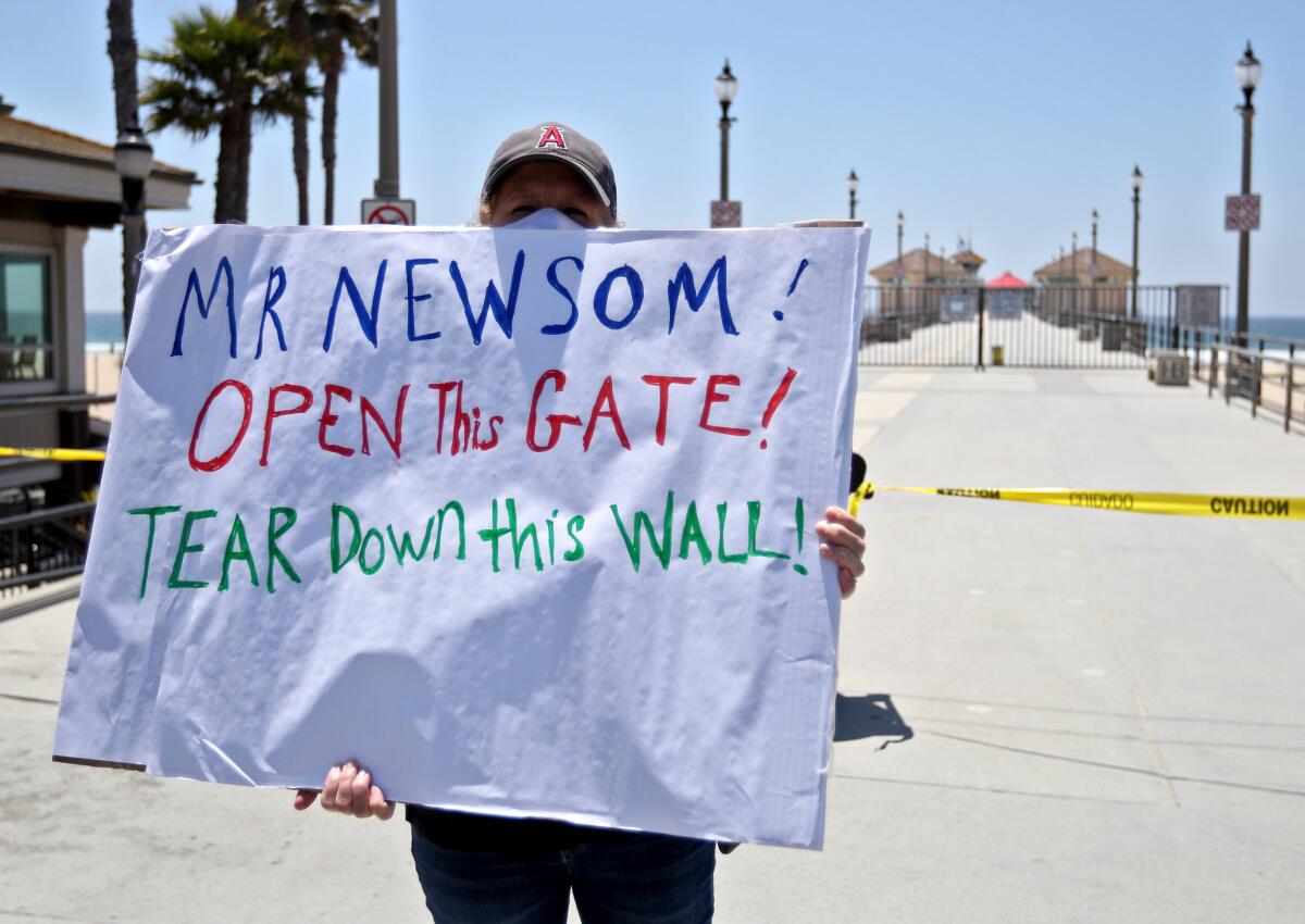 Karen Harris of Dana Point holds a sign during a protest in Huntington Beach in May.