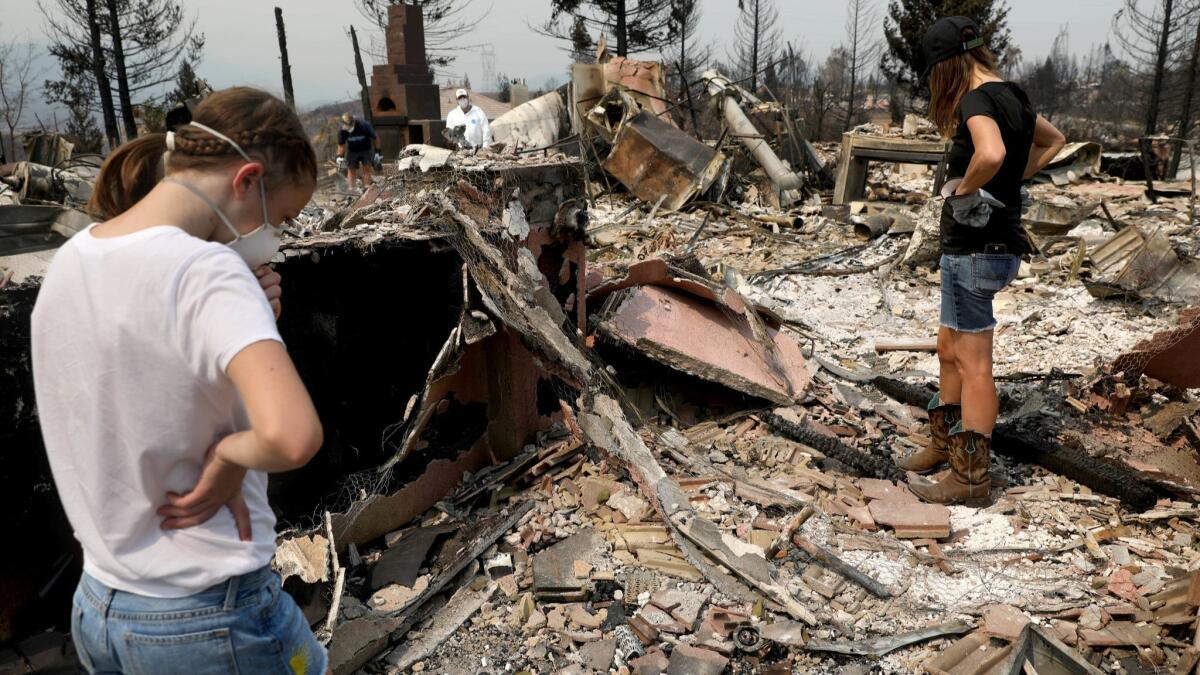 Members of the Gregory family look for valuables last week at their Redding home that burned in the deadly Carr fire. The blaze has destroyed more than 1,000 homes, according to officials.