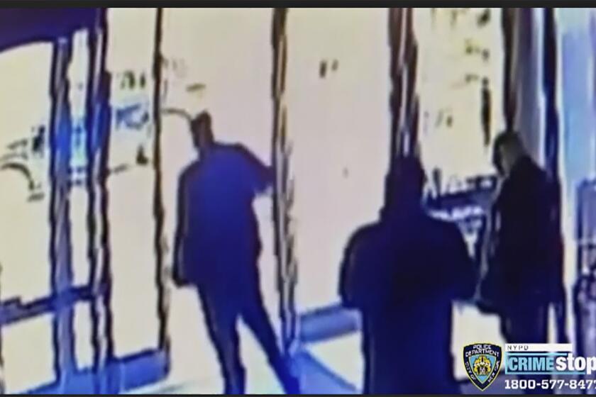 This image taken from surveillance video provided by the New York City Police Department shows an apartment building employee, center, closing the building's front door after a man assaulted a 65-year-old Asian American woman, Monday afternoon, March 29, 2021, a few blocks from New York's Times Square. The property developer and manager of the building wrote on Instagram that it was aware of the assault and said staff members who witnessed it were suspended pending an investigation.(Courtesy of New York Police Department via AP)