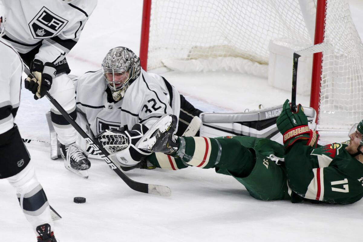 Kings goalie Jonathan Quick stops a shot in front of Minnesota Wild forward Marcus Foligno.