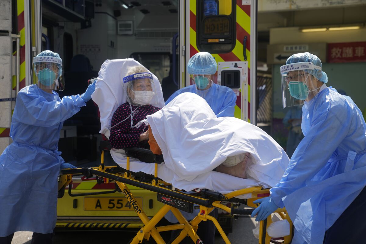 FILE - Medical workers wearing protective gear move an elderly patient from an ambulance to a hospital in Hong Kong, Friday, March 4, 2022. Hong Kong's total coronavirus infections exceeded 1 million on Friday, March 18, 2022, amid a widespread outbreak and thousands of deaths in recent weeks. (AP Photo/Kin Cheung, File)