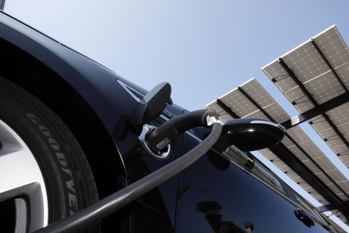 A close-up of an EV's charging port hooked up to a charging cable