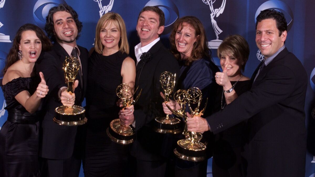 "Sex and the City" stars Kristin Davis, left, and Kim Cattrall, third from left, celebrate the show's Emmy win for best comedy series with producers John Melfi, Michael Patrick King, Cindy Chupach, Jenny Bicks, and Darren Star.