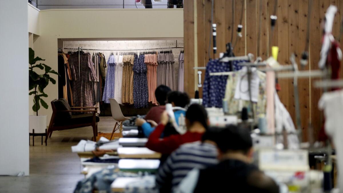 Seamstresses shown in the foreground in the studio space of fashion label Christy Dawn in downtown Los Angeles.