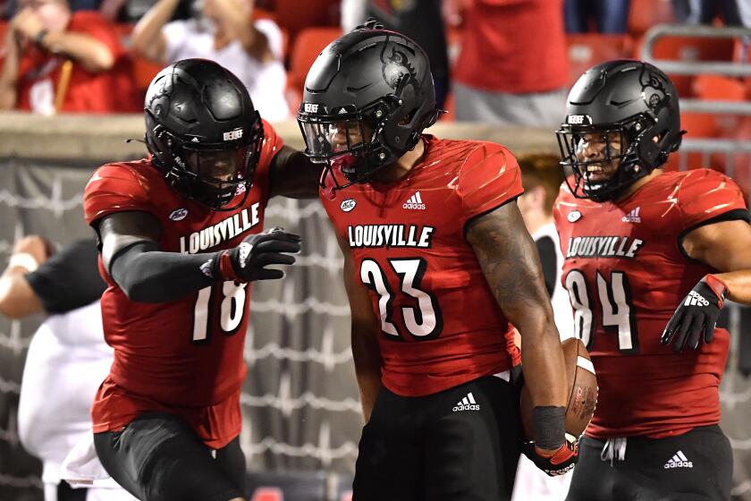 Louisville running back Trevion Cooley (23) celebrates with Justin Marshall (18) and Dez Melton on Sept. 17, 2021.