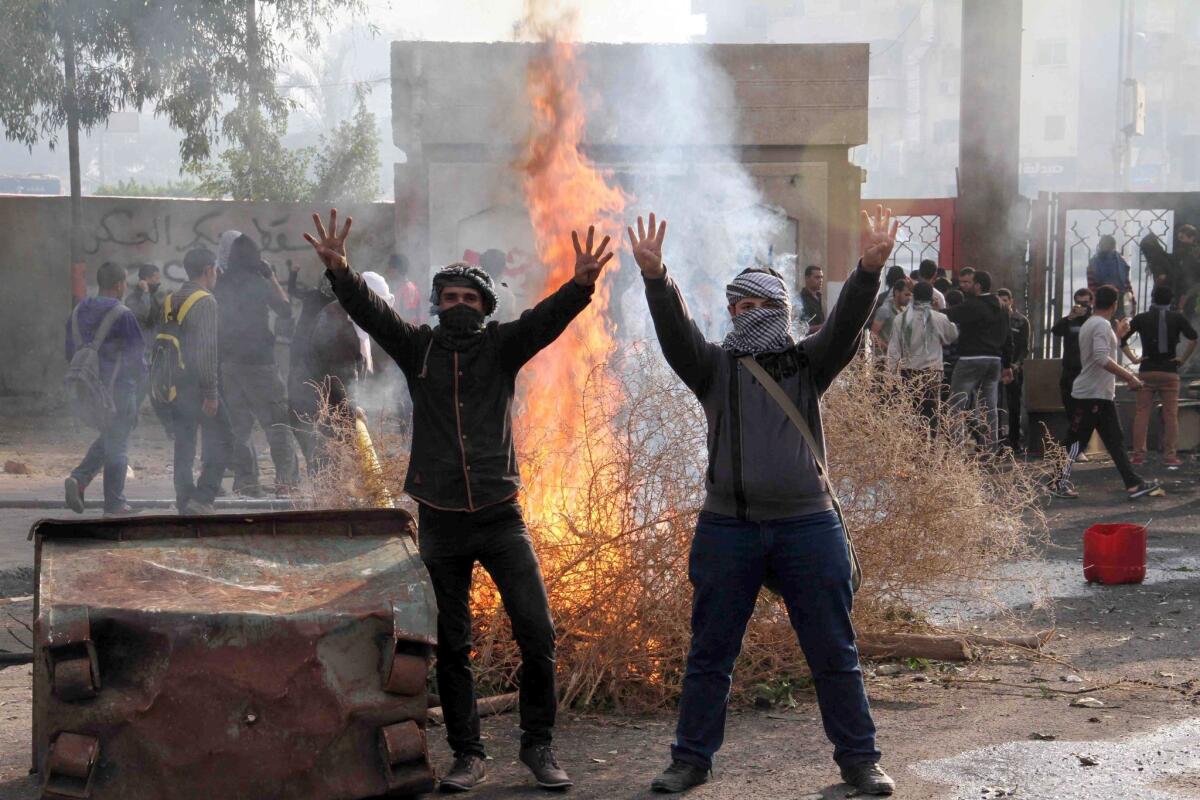 Egyptian students of Al Azhar University who support the Muslim Brotherhood raise their hands showing the four-finger sign -- called Rabaa, or four in Arabic, associated with the crackdown on supporters of ousted Islamist president Mohamed Morsi -- during clashes with riot police in Cairo.