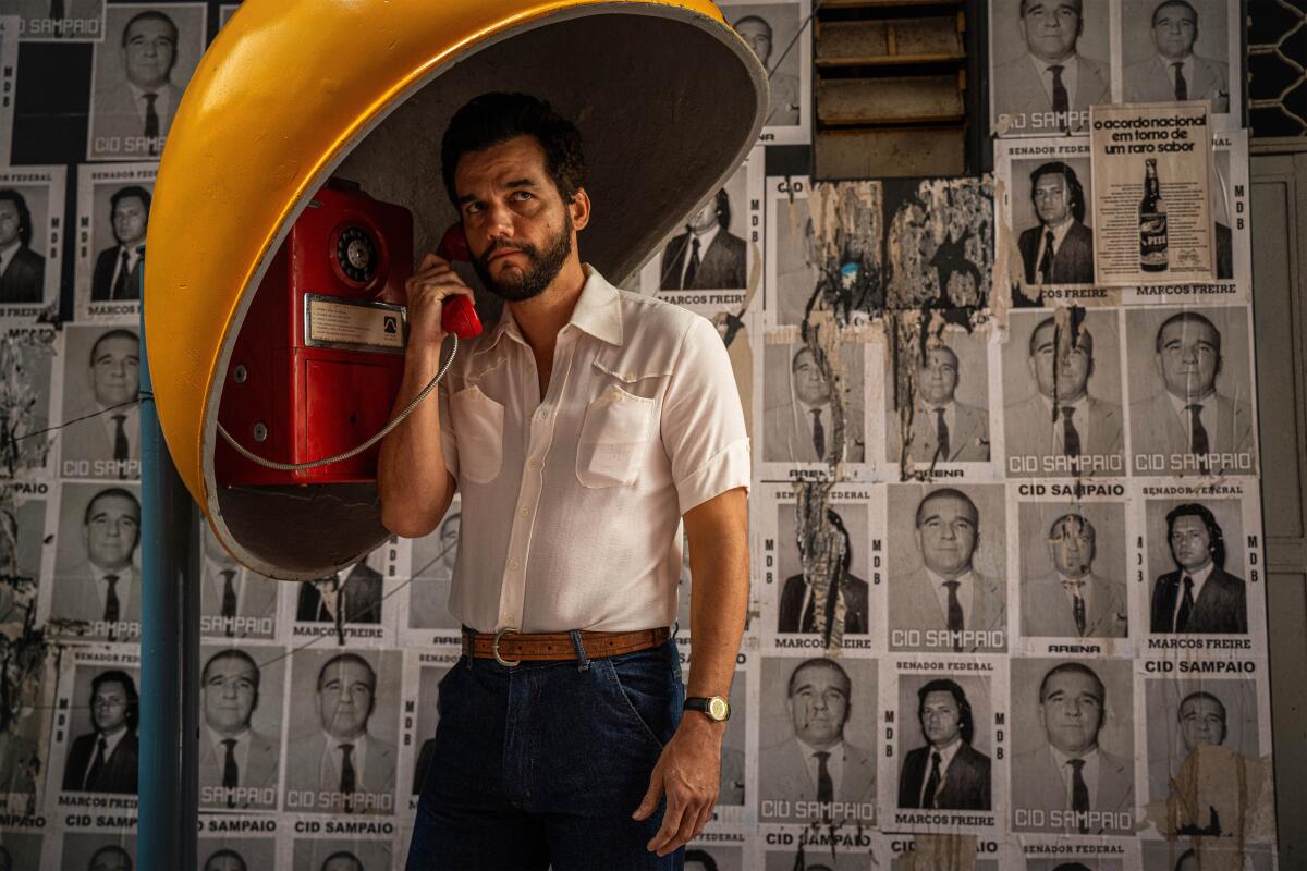 A suspicious man makes a call at a red payphone.
