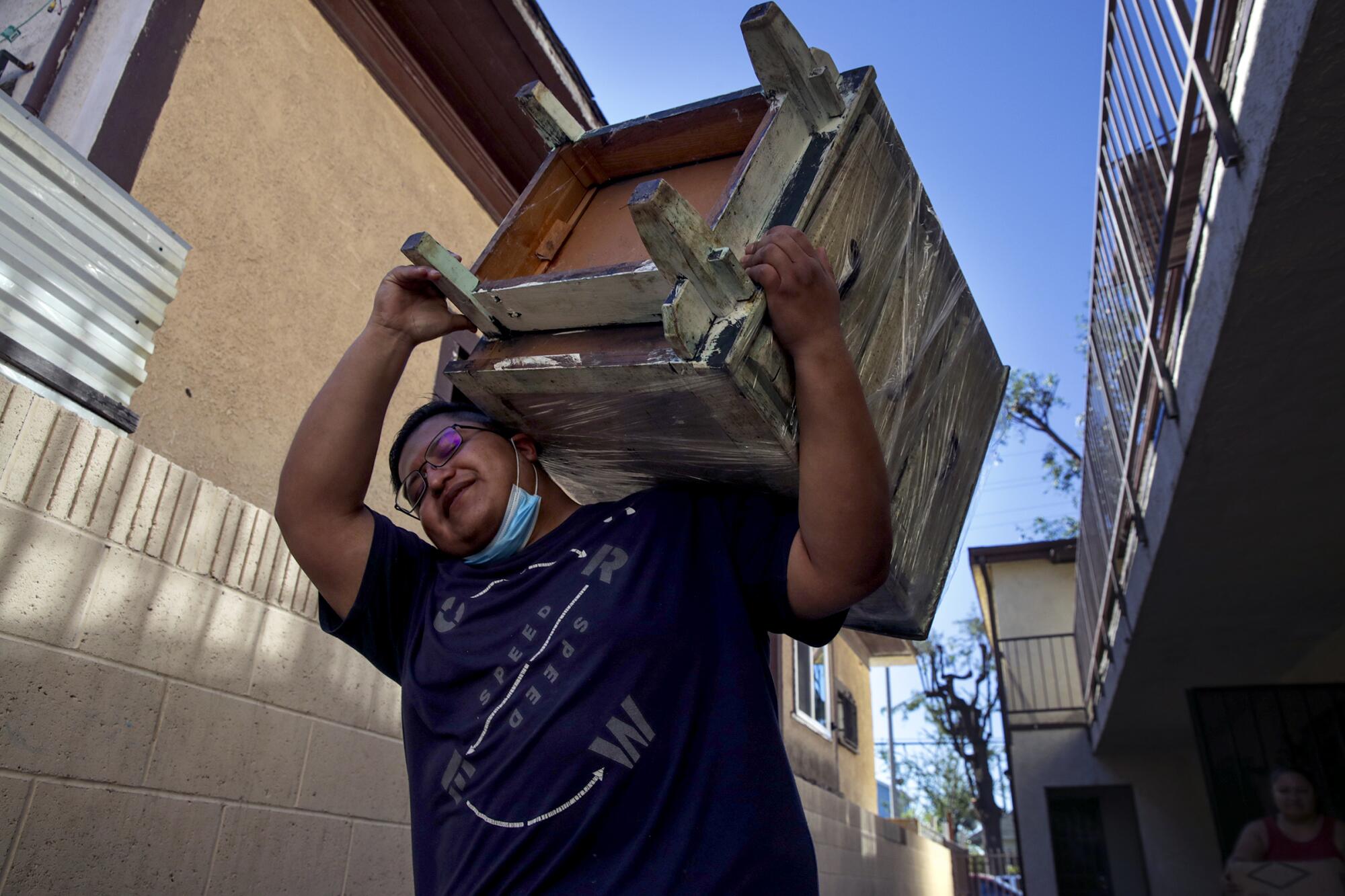 Jafet Martinez Oceguera helps the family move out of their apartment in the 700 block of East 27th Street in South L.A.
