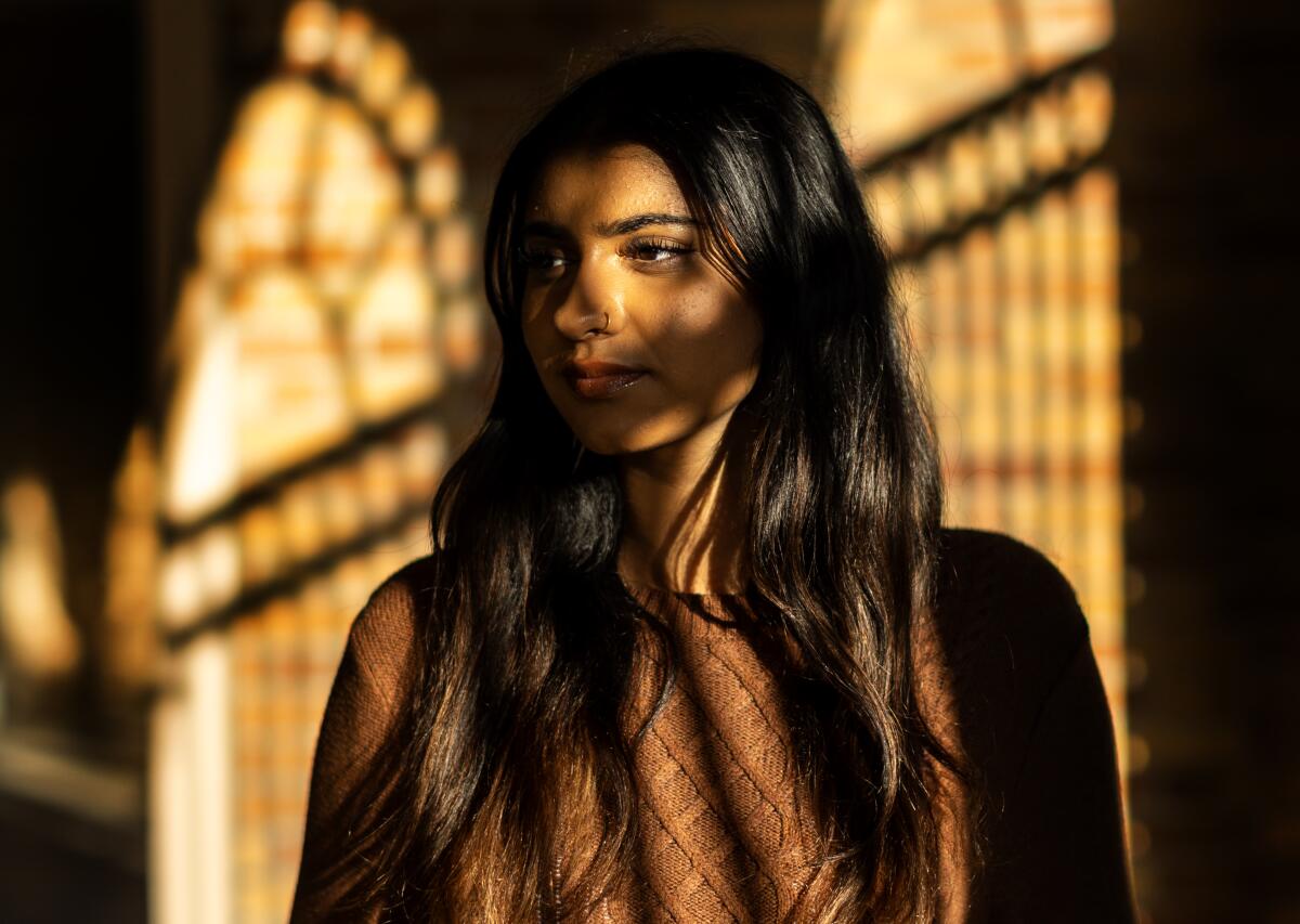 A teenage girl stands partially in shadow.