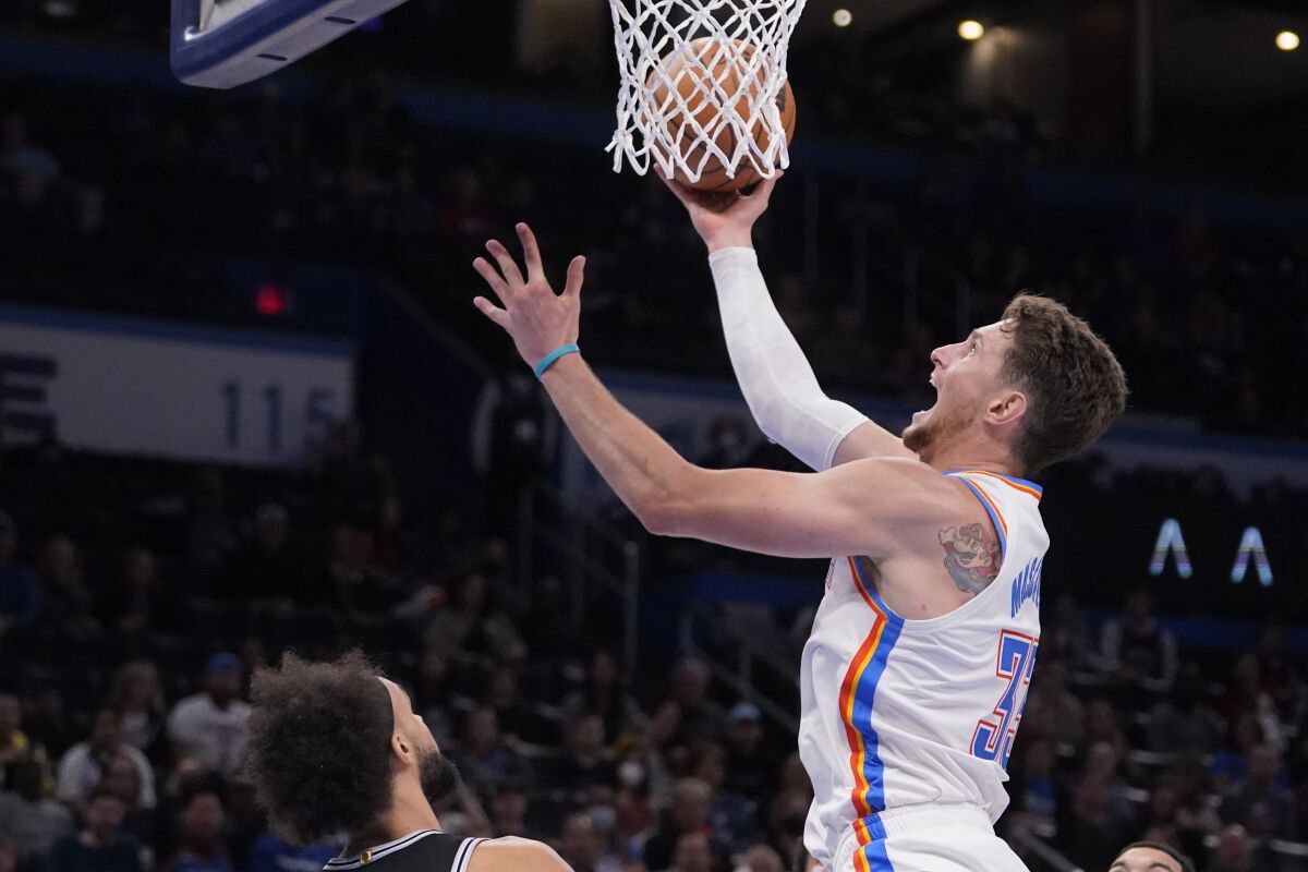 Oklahoma City Thunder center Mike Muscala (33) shoots in front of San Antonio Spurs guard Derrick White, left, in the second half of an NBA basketball game Sunday, Nov. 7, 2021, in Oklahoma City. (AP Photo/Sue Ogrocki)