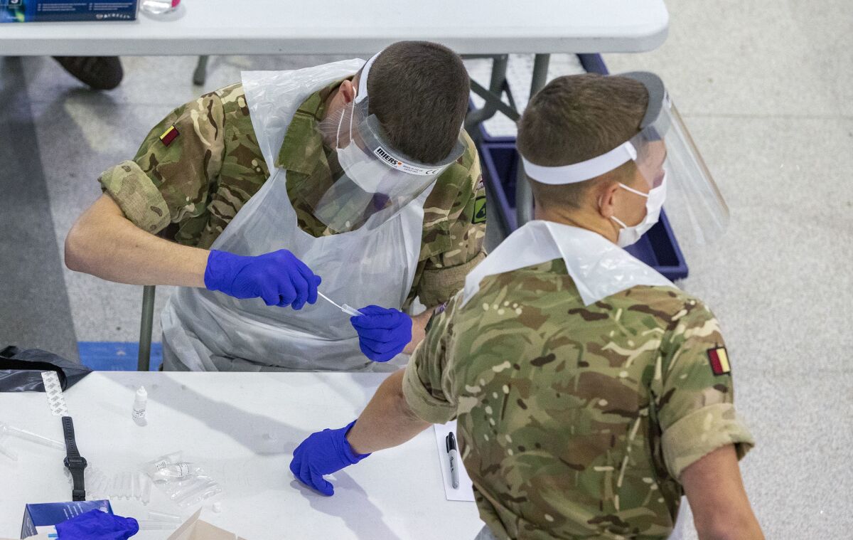 Soldiers carry out mass coronavirus testing, set up at a marketplace in Liverpool, England, during the four-week national lockdown to curb the spread of coronavirus in England, Wednesday Nov. 11, 2020. Everyone in Liverpool city, are being encouraged to be tested for COVID-19, even if they are not displaying symptoms, as authorities continue a mass testing pilot scheme to suppress the coronavirus.(Peter Byrne/PA via AP)