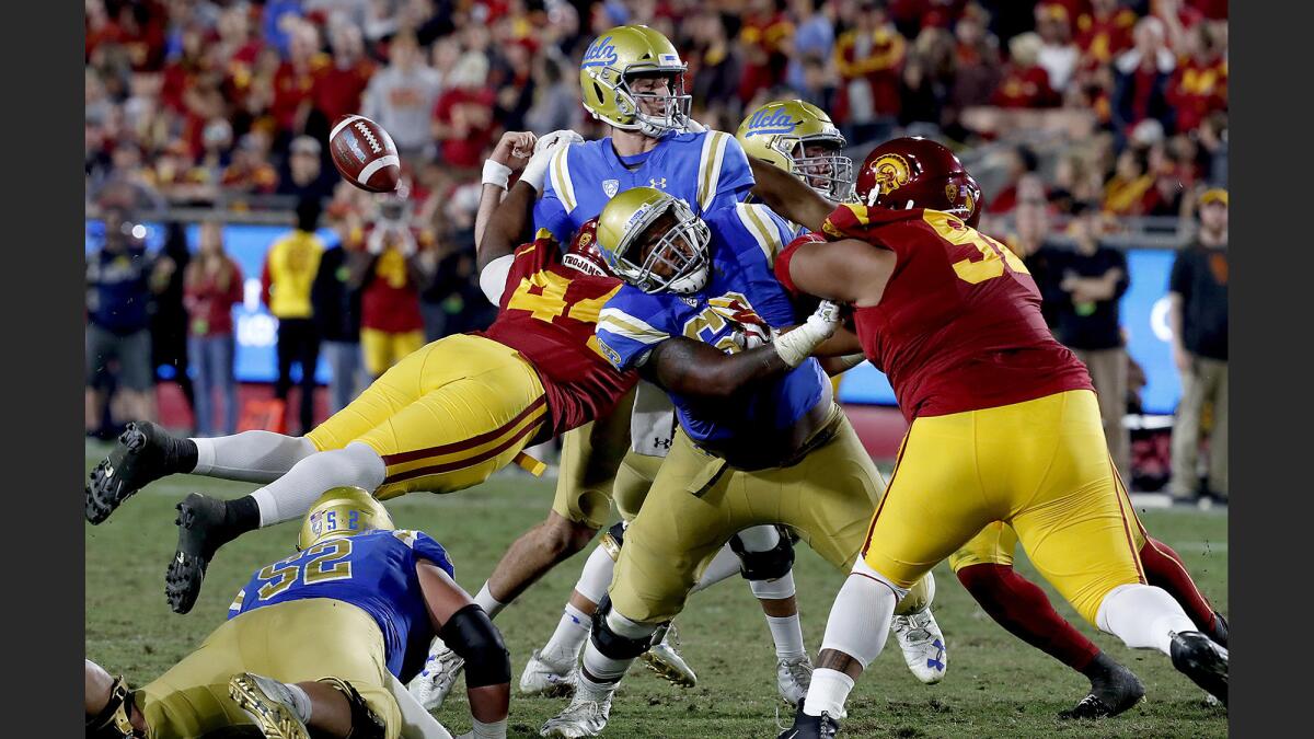 UCLA quarterback Josh Rosen loses control of the ball as the USC defense closes in on him during the second quarter of a game Saturday at the Coliseum.