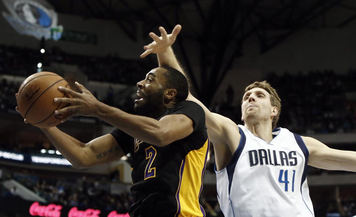 Lakers guard Wayne Ellington avoids the block attempt of Mavericks forward Dirk Nowitzki for a layup in the first half.