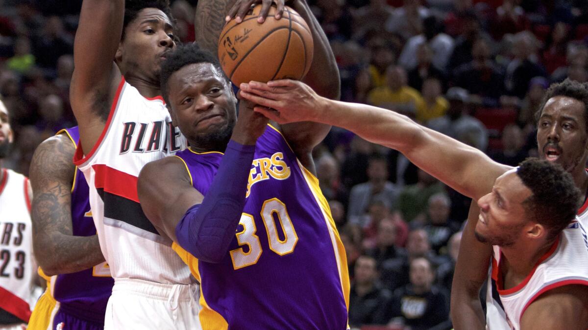 Lakers forward Julius Randle (30) tries to power his way to the basket against Trail Blazers center Ed Davis and guard Evan Turner, right, during the first half Thursday.