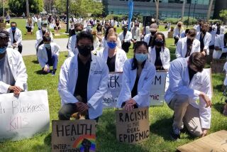Scores of US San Diego medical students and others kneel down during an anti-racism rally at the La Jolla campus at noon Monday.