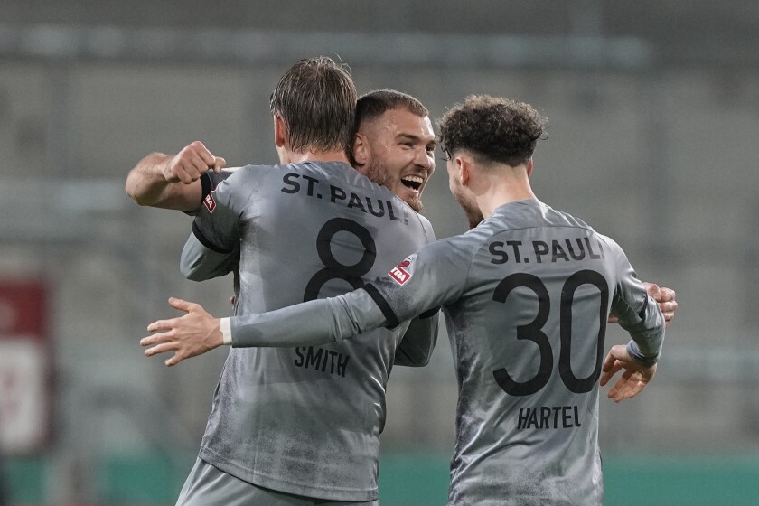 ST. Pauli's Eric Smith, Maximilian Dittgen and Marcel Hartel, from left, celebrates at the en of the German Soccer Cup round of 16 soccer match between FC St. Pauli and Borussia Dortmund in Hamburg, Germany, Tuesday, Jan. 18, 2022. St. Pauli won 2-1. (AP Photo/Martin Meissner)