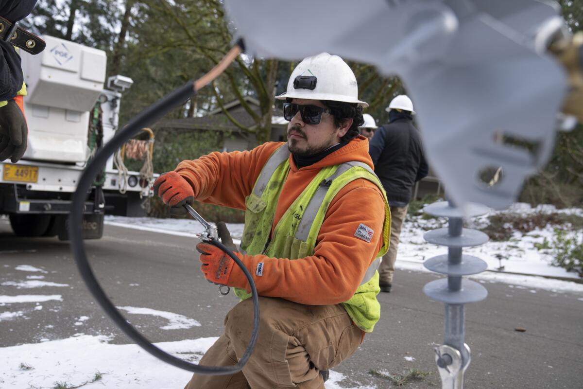 ARCHIVO -Un trabajador de Portland General Electric reemplaza un cable de alta tensión