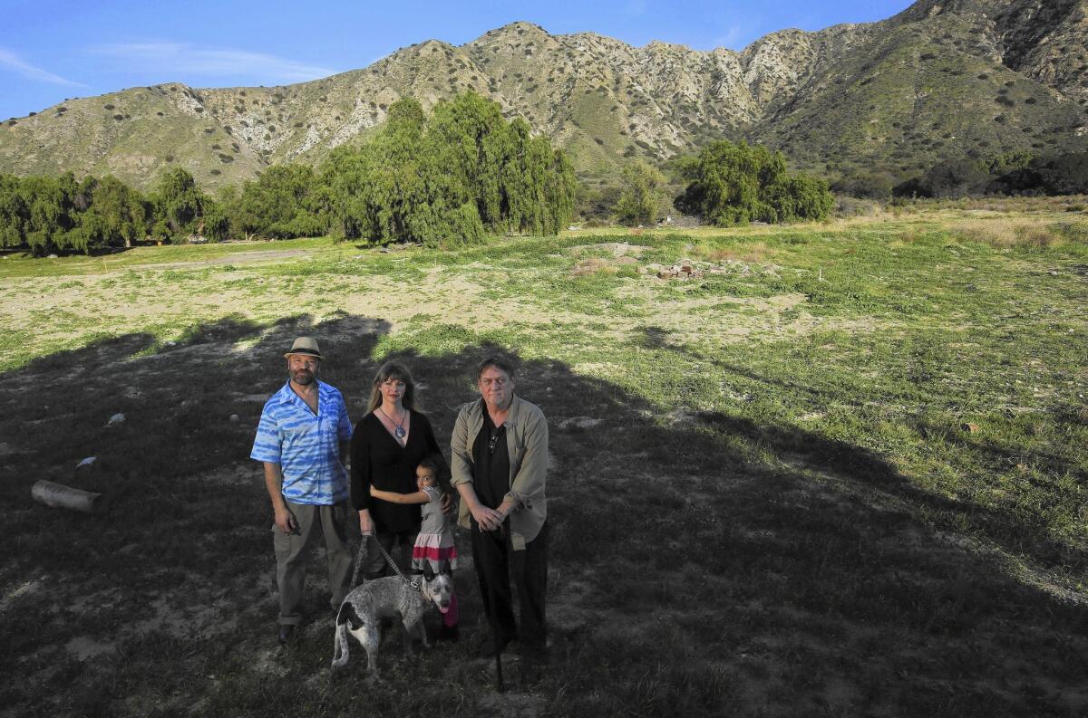 Sunland-Tujunga residents Mark Legassie, Charlene Mason Gallego, her daughter Olivia Gallego, 5, their dog Kayte and Joe Barrett pose at the area along Big Tujunga Canyon Road where a developer is proposing to build 242 homes.