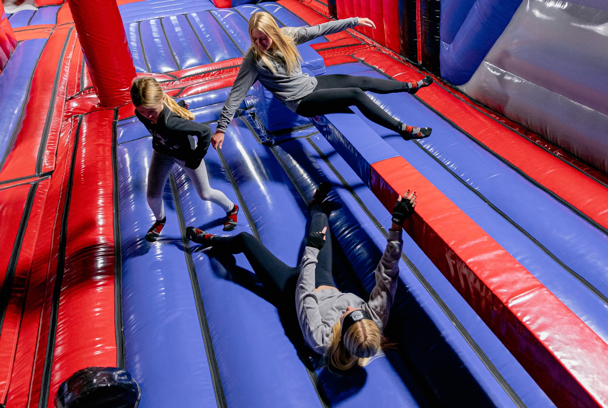 Three girls play on an inflatable obstacle course.