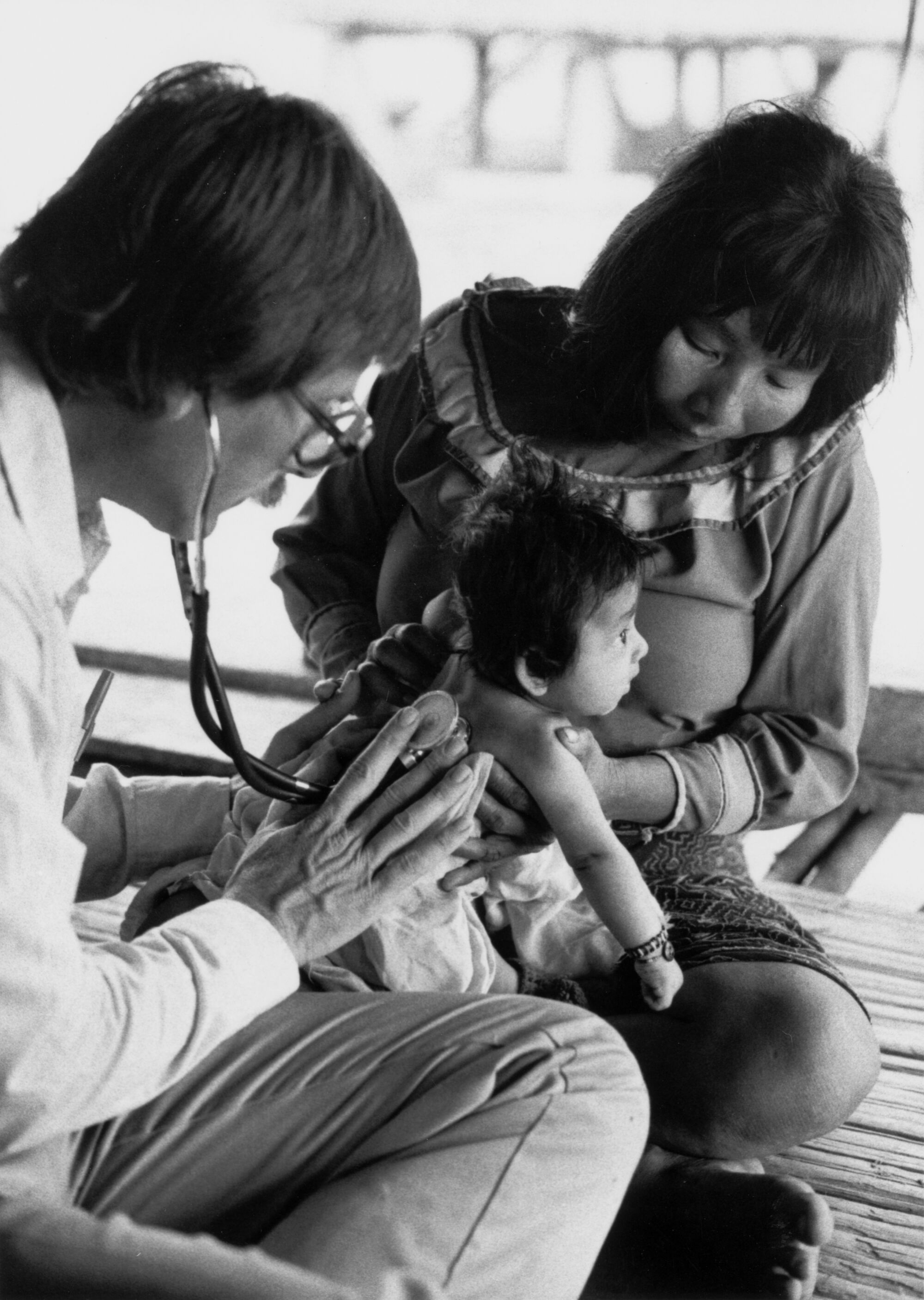 Dr. Warren Hern listening to a baby's lungs in the Amazon rainforest in Peru.