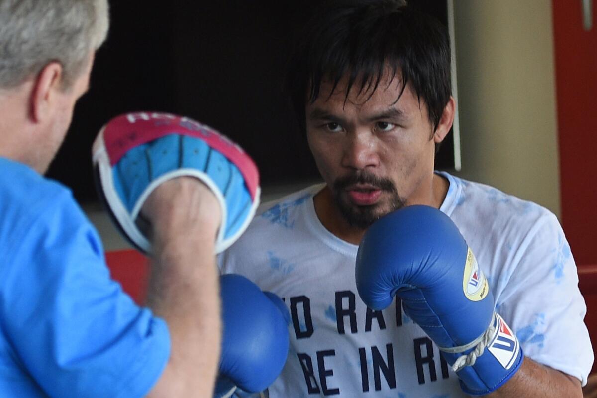 Boxer Manny Pacquiao spars with coach Freddie Roach as part of his training at a gym in General Santos City in the southern Philippine island of Mindanao.