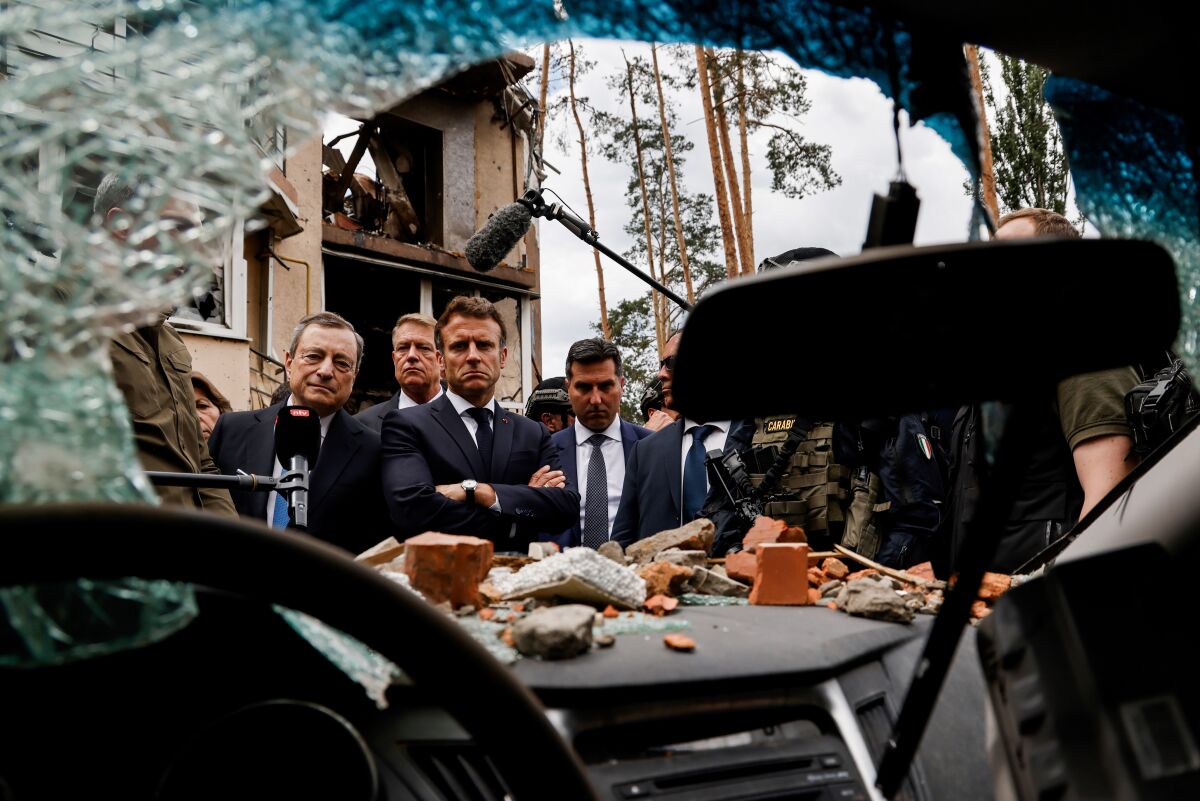 Italian Prime Minister Mario Draghi, left, and French President Emmanuel Macron watch debris as they visit Irpin, Ukraine.