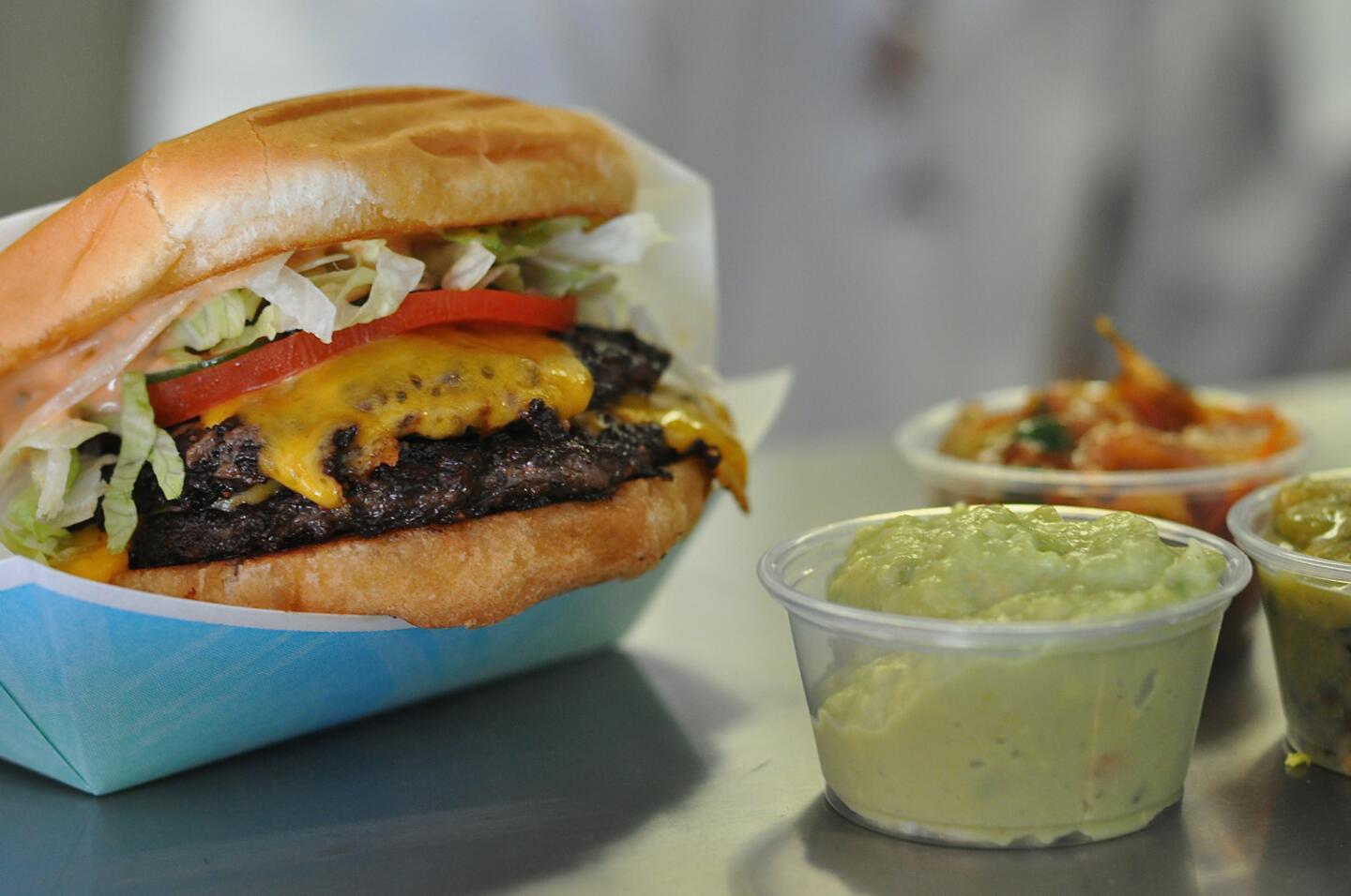 A double cheeseburger, green curry guacamole and other sauces wait on the pass at the new Hamburguesa Punta Cabras in downtown Los Angeles.