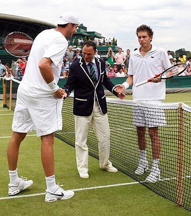U.S. player John Isner, left, and Nicolas Mahut of France, right, talk with chair umpire Mohamed Lahyani before resuming their their epic men's singles match at the All England Lawn Tennis Championships at Wimbledon on Thursday. The match began Tuesday, was suspended because of darkness twice and was resumed with the scores tied at 59 all in the fifth set.