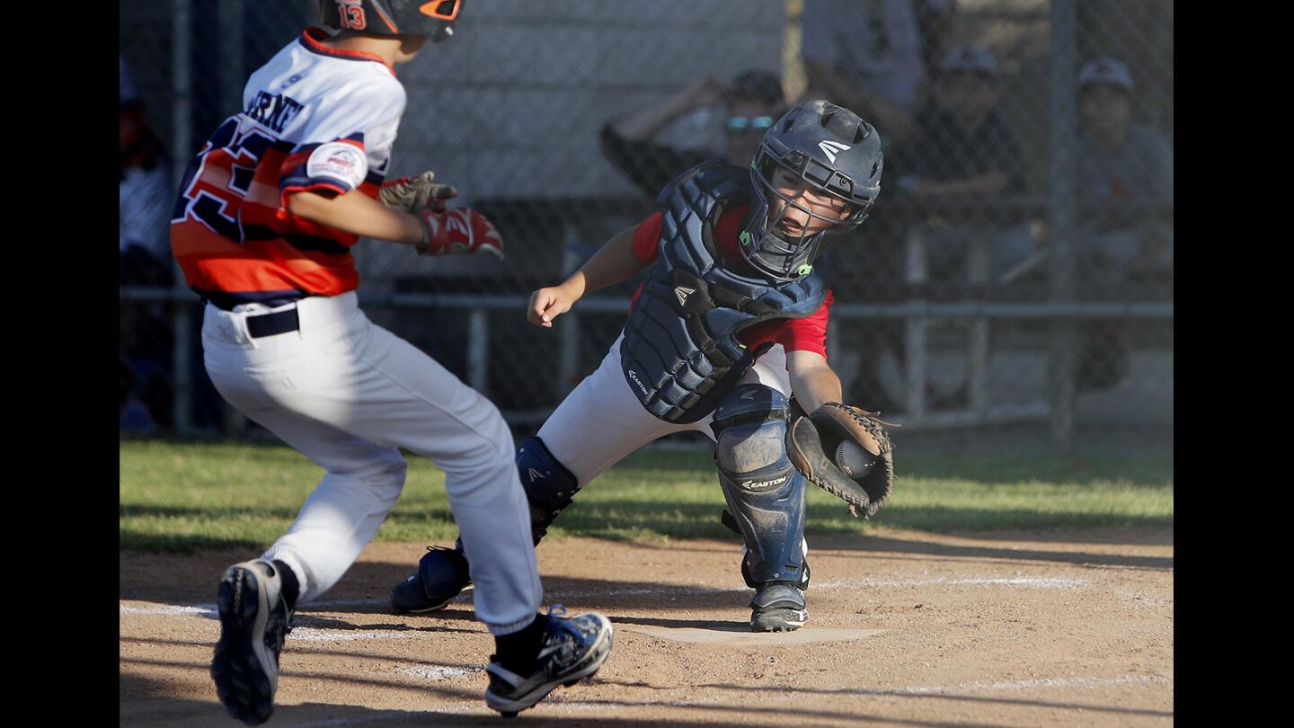Newport Beach Baseball Association 11-and-under Grey-B catcher Marc Solomon saves a run with a tag on Placentia's Pierce Werner during the fifth inning at the St. Hedwig All-Star Invitational in Los Alamitos on Tuesday, June 12.