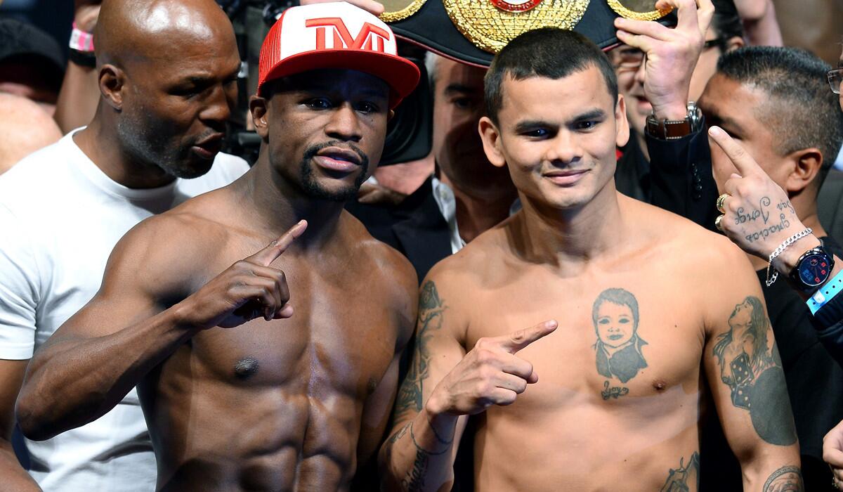 Floyd Mayweather Jr. (wearing hat) and Marcos Maidana each flash the No. 1 sign after their weigh-in at the MGM Grand Garden Arena on Friday.