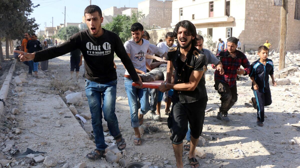 Syrians carry a stretcher as they evacuate victims from the rubble of a collapsed building after a reported U.S. airstrike in northern Syria on July 19.