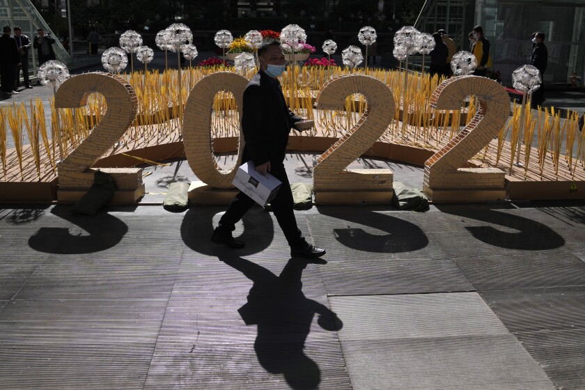 A man wearing a mask walks past the 2022 sign outside an office building on Monday, March 7, 2022, in Beijing. China is seeing a new surge in COVID-19 cases across the vast country, despite its draconian "zero tolerance" approach to dealing with outbreaks. (AP Photo/Ng Han Guan)