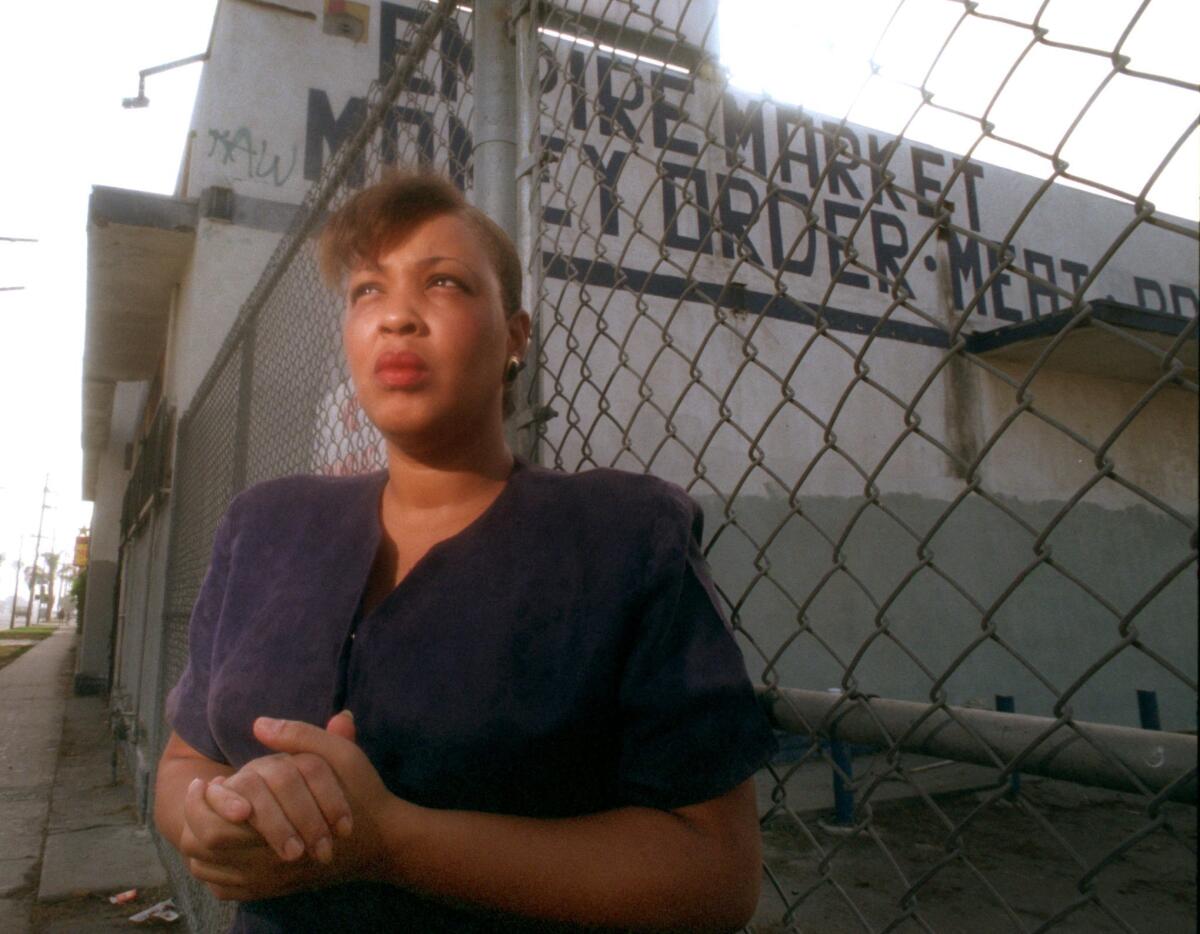 A woman clasps her hands while standing in front of a chain-link fence