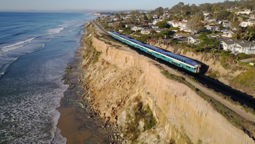 A Coaster train heads southbound along cliffs in Del Mar where tracks are less a few feet from crumbling edges.