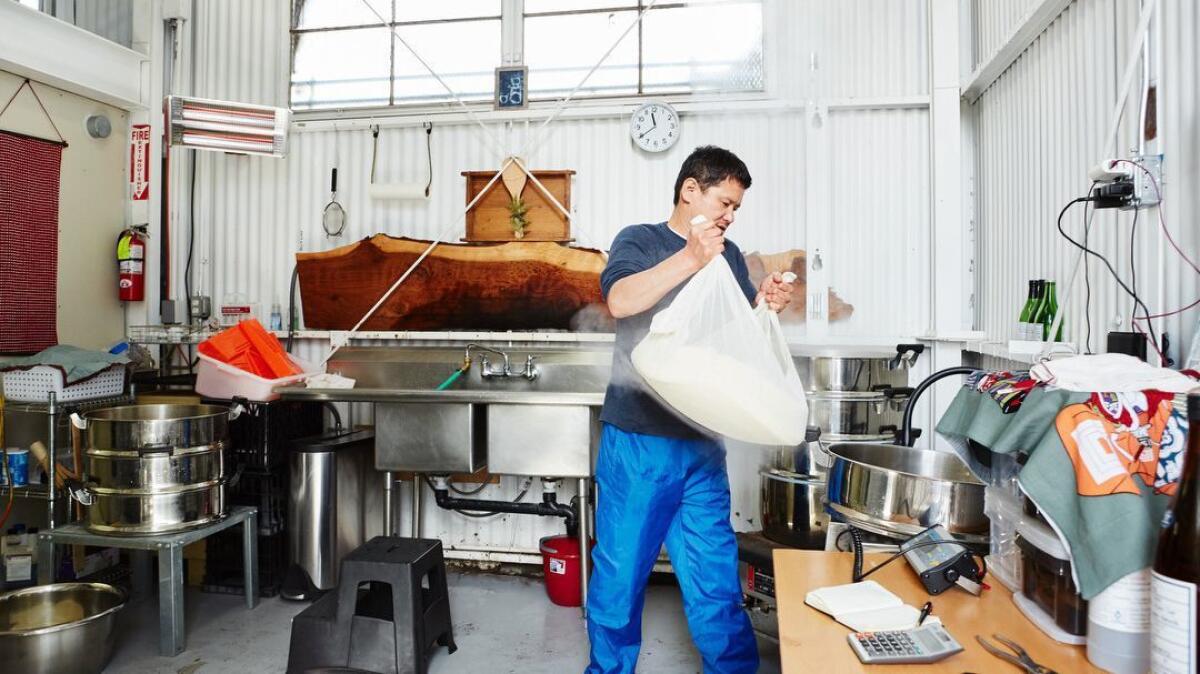 Yoshihiro Sako weighs steamed rice to brew sake at Den Sake Brewery.