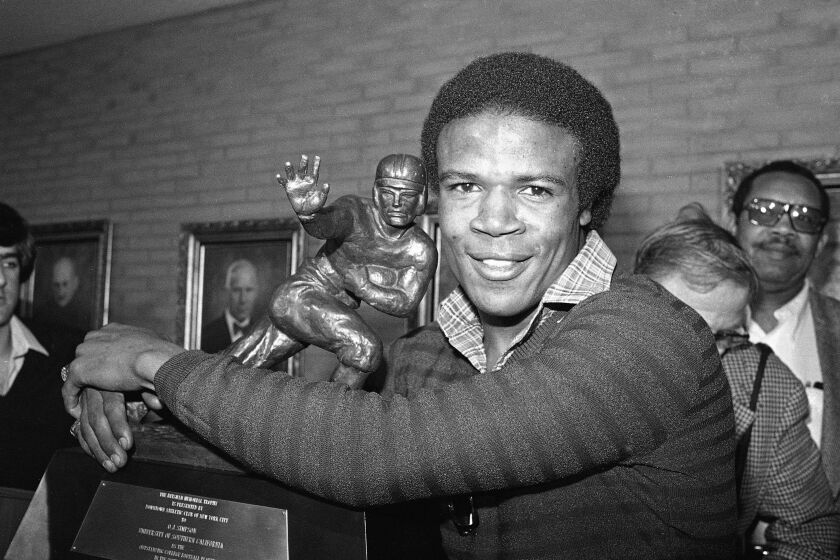 Tailback Charles White of the USC Trojans, puts his arms around the Heisman Trophy won by O.J. Simpson in 1968 after he was announce the winner of the 1979 Heisman Trophy in Los Angeles, Calif., Dec. 3, 1979. White is the second leading rusher in college football history. White's Heisman is the third for USC, along with Simpson and Mike Garrett in 1964. (AP Photo/Wally Fong)