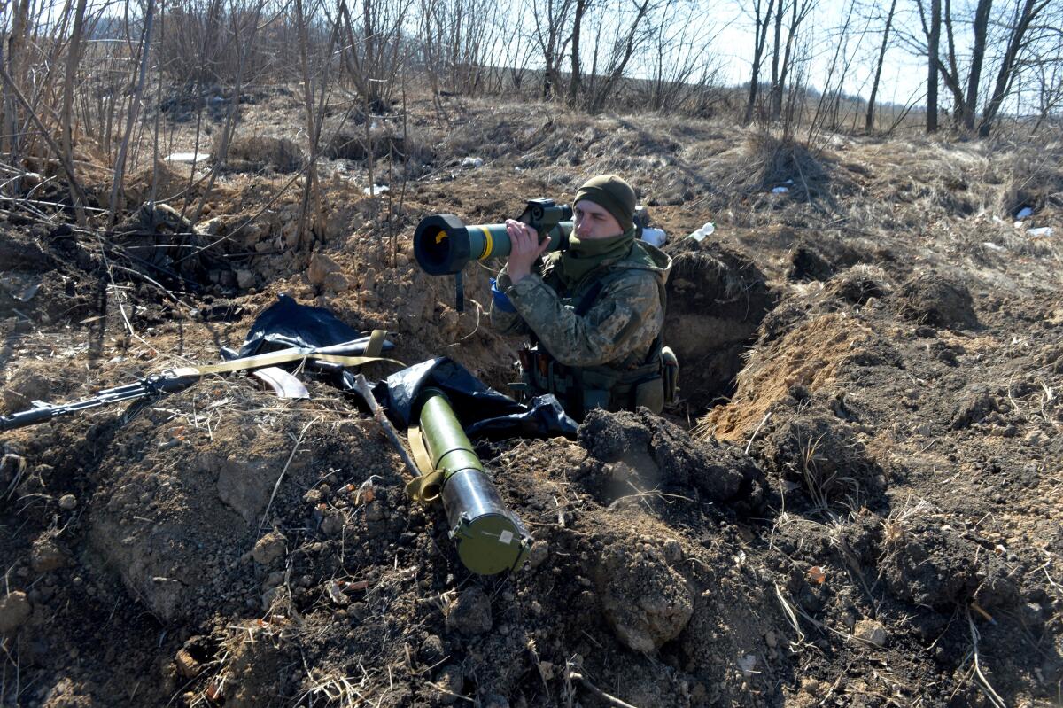 A Ukrainian soldier holds a weapon in a foxhole.